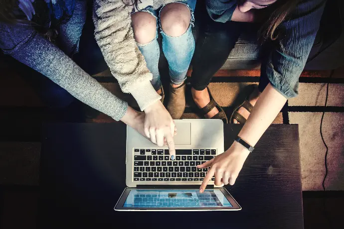 three person pointing the silver laptop computer